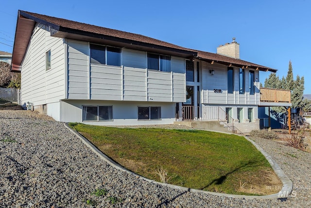 rear view of property featuring a balcony and a yard