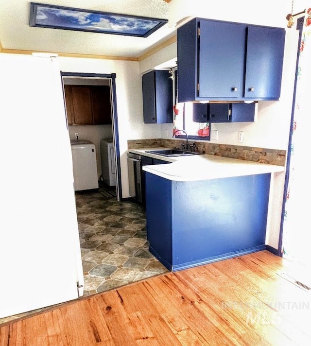 kitchen with washer and dryer, blue cabinetry, and sink