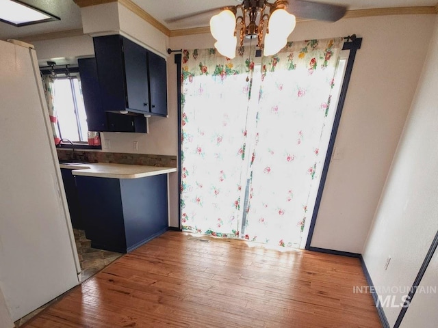 kitchen with light hardwood / wood-style floors, sink, ornamental molding, and an inviting chandelier