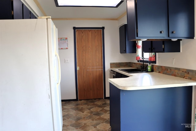 kitchen with blue cabinets, sink, and white fridge