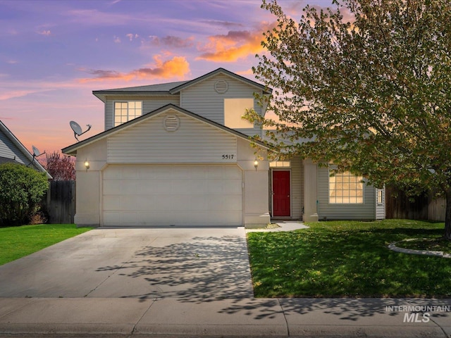 traditional-style home featuring a front yard, driveway, a garage, and fence