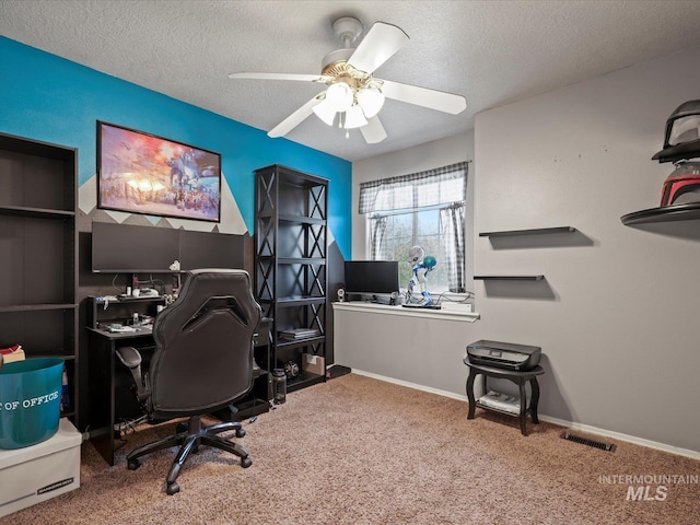 carpeted home office featuring a textured ceiling, visible vents, a ceiling fan, and baseboards