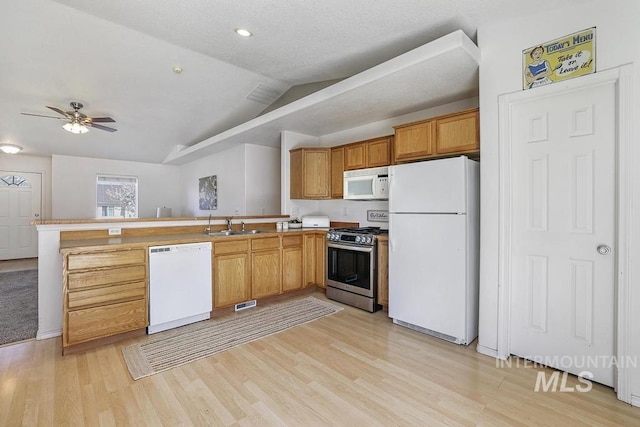 kitchen with a peninsula, lofted ceiling, white appliances, and light wood-style flooring