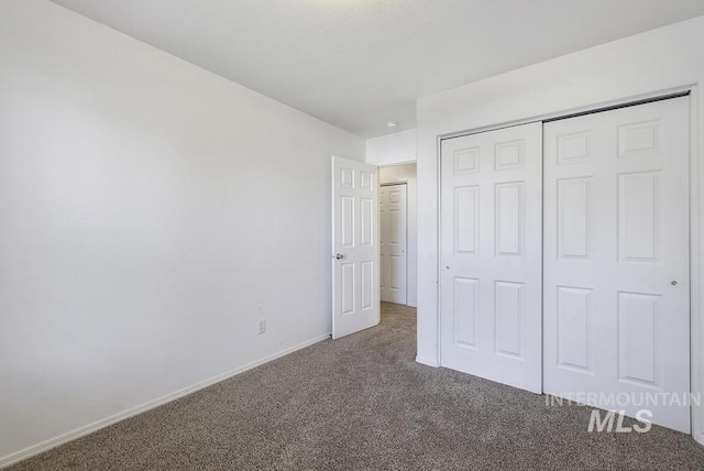 unfurnished bedroom with a closet, carpet flooring, and baseboards