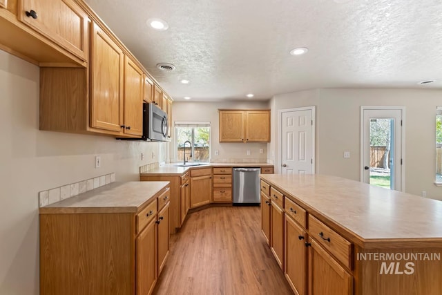 7362 S Shadowmoss Ave, Boise, ID 83709 - kitchen with stainless steel appliances, a sink, light wood finished floors, a textured ceiling, and recessed lighting