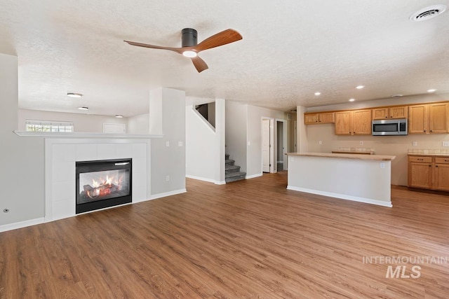 7362 S Shadowmoss Ave, Boise, ID 83709 - unfurnished living room with light wood-type flooring, stairway, a textured ceiling, baseboards, and recessed lighting