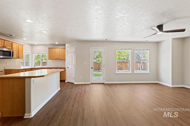 7362 S Shadowmoss Ave, Boise, ID 83709 - kitchen featuring stainless steel microwave, dark wood-style floors, recessed lighting, a textured ceiling, and light countertops