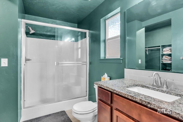 full bathroom with a shower stall, toilet, vanity, and a textured ceiling