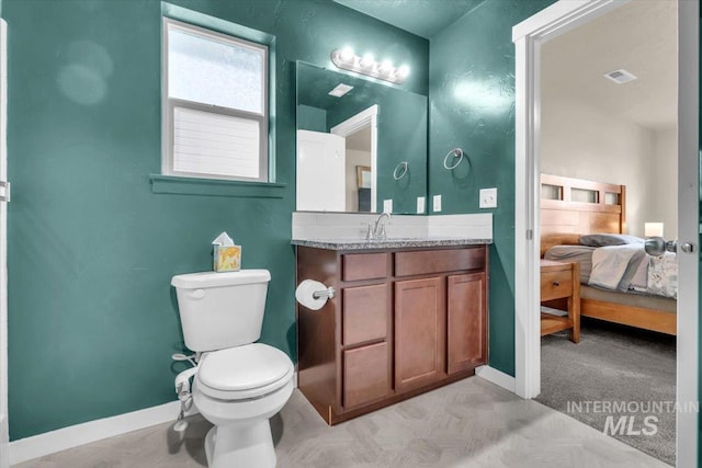 ensuite bathroom featuring toilet, baseboards, and vanity