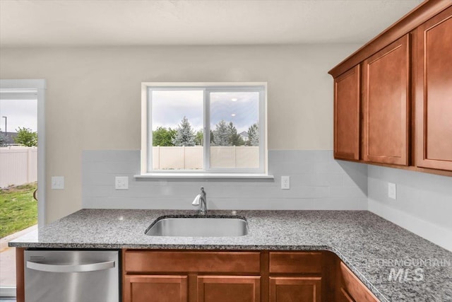 kitchen featuring a sink, stainless steel dishwasher, light stone counters, and brown cabinets