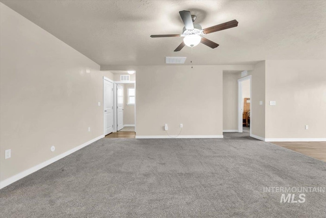 carpeted empty room with a ceiling fan, baseboards, and a textured ceiling