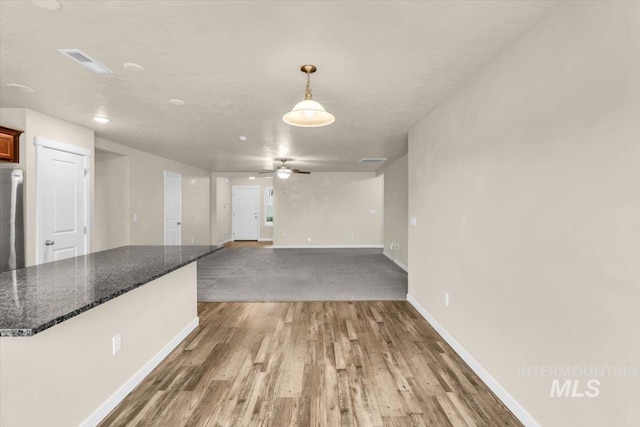 unfurnished living room featuring baseboards, wood finished floors, and ceiling fan