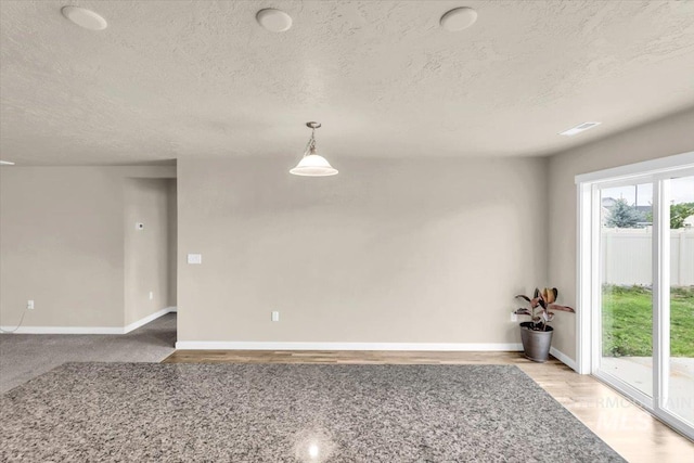 spare room with a textured ceiling and baseboards