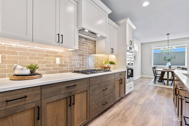 1501 E Andes Dr, Kuna, ID 83634 - kitchen featuring appliances with stainless steel finishes, light wood-type flooring, white cabinets, tasteful backsplash, and recessed lighting
