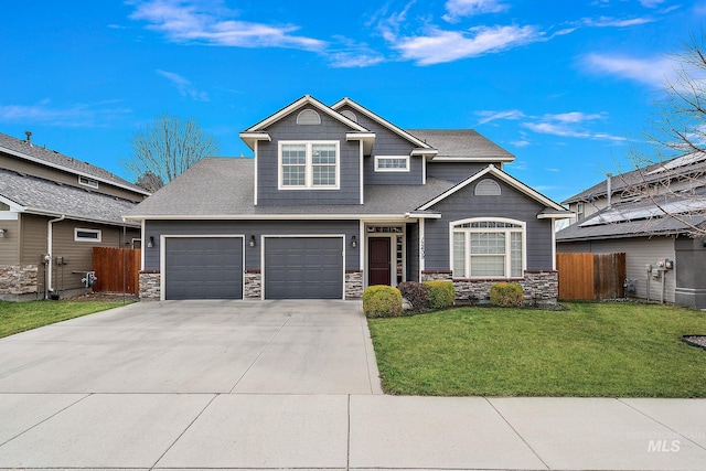 craftsman-style house featuring a front lawn, fence, stone siding, and driveway