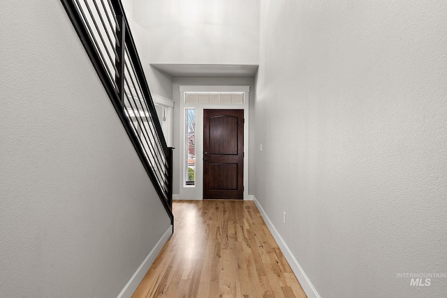 entrance foyer with baseboards, a high ceiling, and light wood finished floors