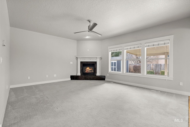 unfurnished living room with baseboards, a premium fireplace, carpet flooring, a textured ceiling, and a ceiling fan