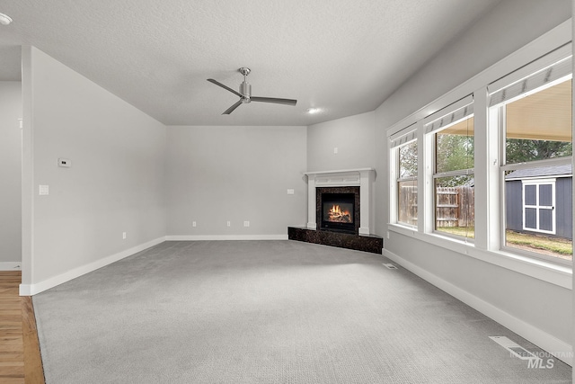 unfurnished living room featuring visible vents, a fireplace, a textured ceiling, and baseboards