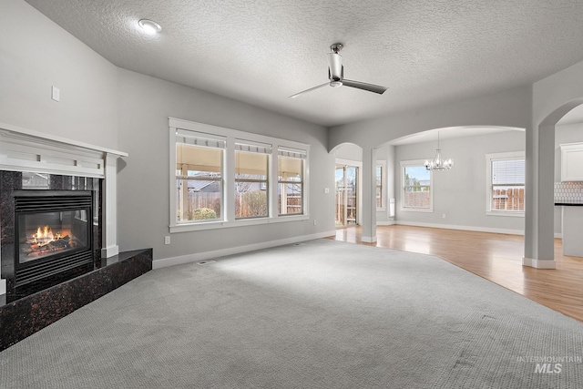 unfurnished living room featuring a ceiling fan, visible vents, carpet floors, a fireplace, and arched walkways