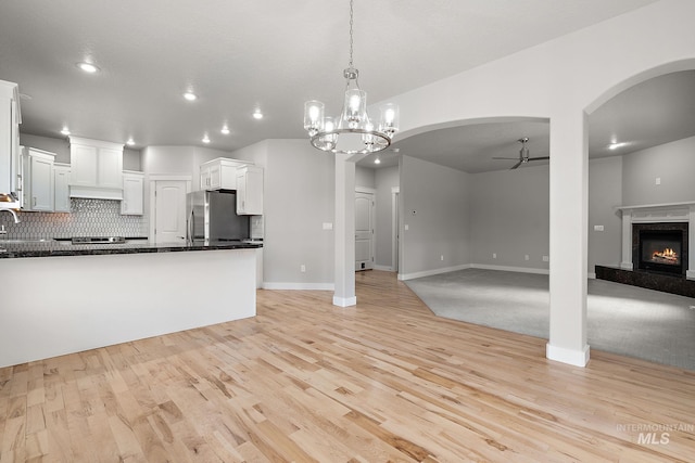 kitchen with backsplash, open floor plan, freestanding refrigerator, a fireplace, and ceiling fan