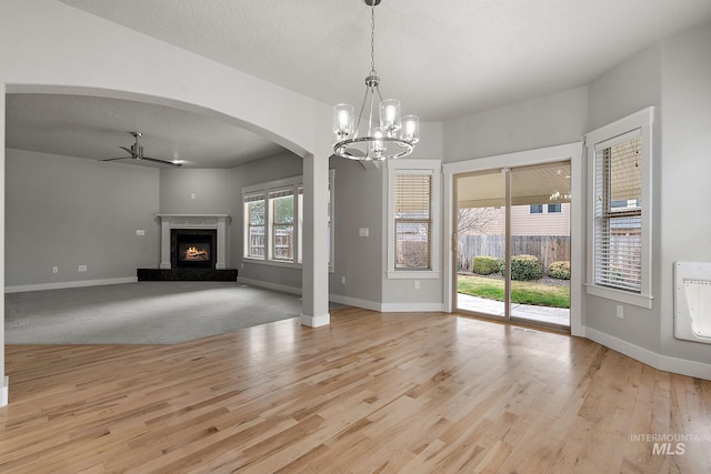 unfurnished living room featuring baseboards, wood finished floors, ceiling fan, and a fireplace