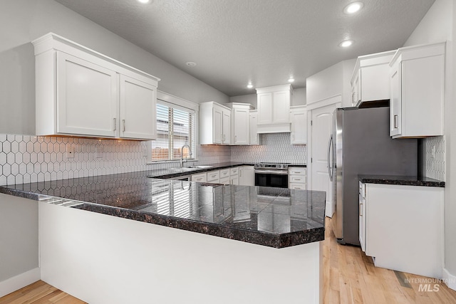 kitchen with light wood-style flooring, a sink, appliances with stainless steel finishes, a peninsula, and white cabinets