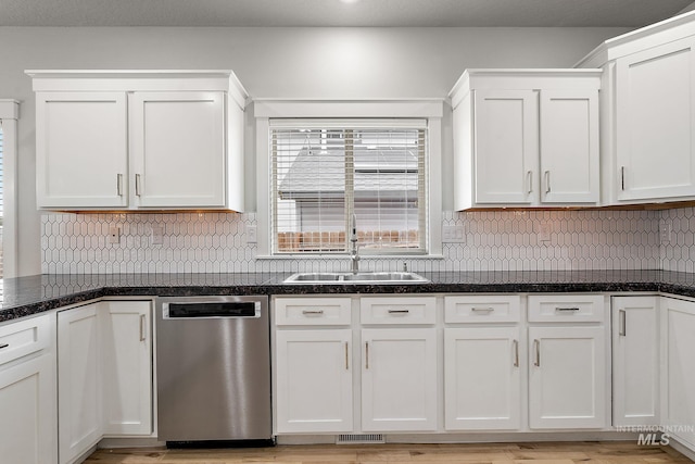 kitchen featuring stainless steel dishwasher, tasteful backsplash, white cabinetry, and a sink