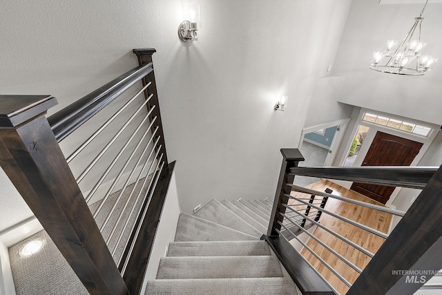 staircase featuring an inviting chandelier and wood finished floors