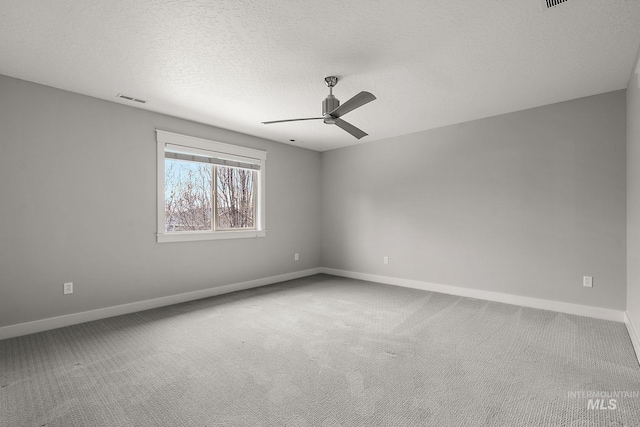 spare room with a ceiling fan, baseboards, visible vents, carpet floors, and a textured ceiling