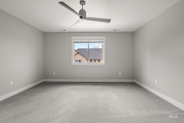 carpeted spare room featuring baseboards, a textured ceiling, and a ceiling fan