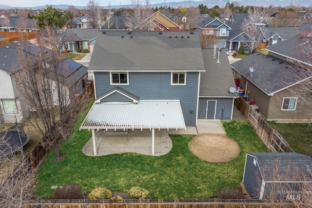 rear view of house featuring a fenced backyard, a residential view, a patio, and a yard