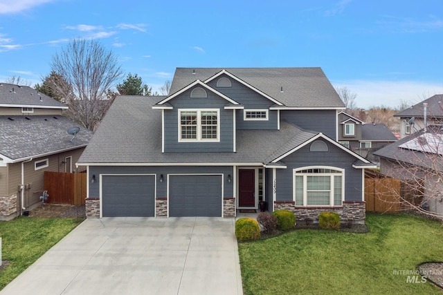 craftsman inspired home featuring fence, concrete driveway, a front lawn, a garage, and stone siding