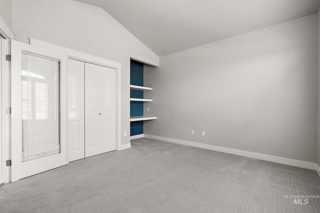 unfurnished bedroom with a closet, baseboards, carpet, and vaulted ceiling