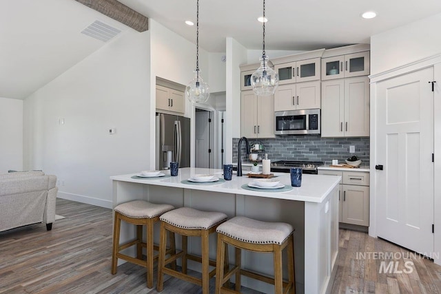 958 Gregory Way, Twin Falls, ID 83301 - kitchen featuring appliances with stainless steel finishes, vaulted ceiling, dark wood-style flooring, a kitchen bar, and tasteful backsplash