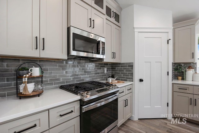 958 Gregory Way, Twin Falls, ID 83301 - kitchen with appliances with stainless steel finishes, backsplash, wood finished floors, light countertops, and glass insert cabinets