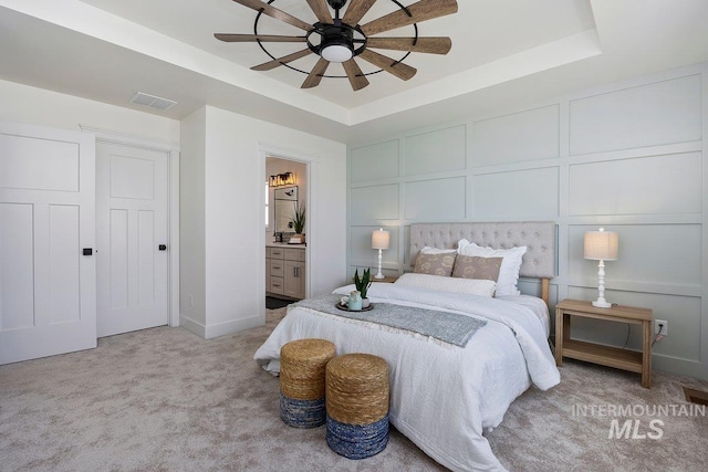 958 Gregory Way, Twin Falls, ID 83301 - bedroom featuring a raised ceiling, a decorative wall, light carpet, connected bathroom, and baseboards