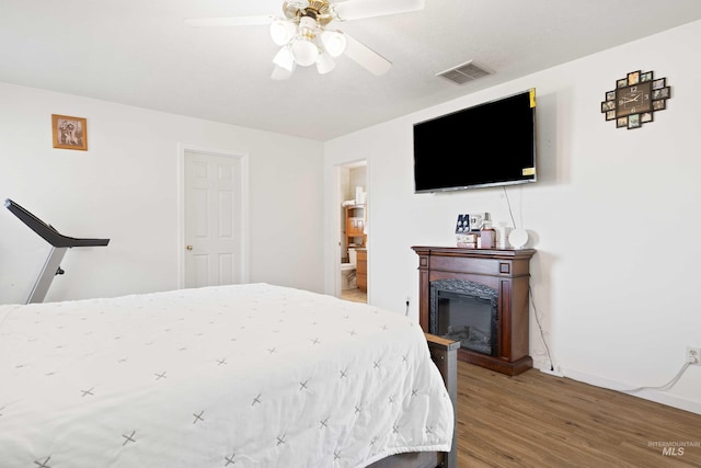 bedroom featuring hardwood / wood-style flooring, ceiling fan, and connected bathroom