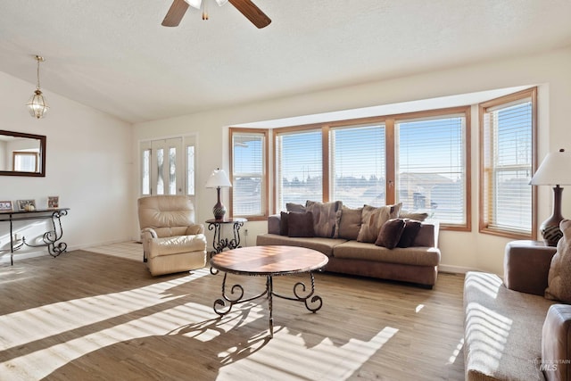 living room featuring ceiling fan, light wood-type flooring, and vaulted ceiling