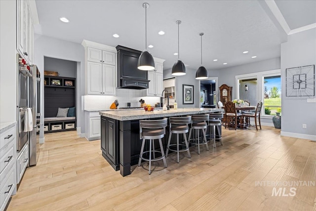1427 N Morehouse, Eagle, ID 83616 - kitchen with a kitchen breakfast bar, light wood-style flooring, a center island with sink, white cabinetry, and backsplash