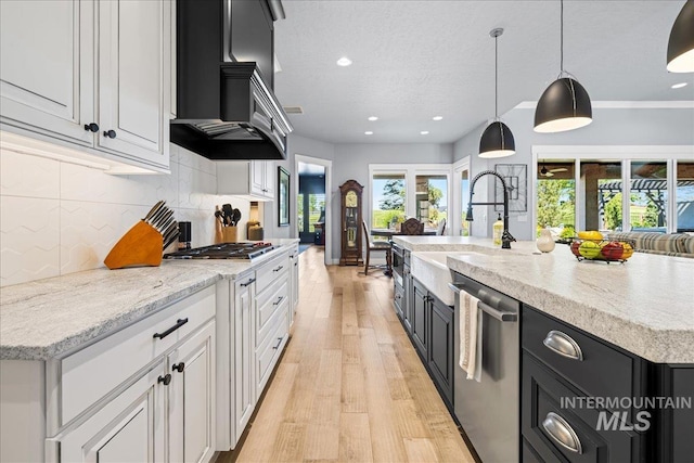 1427 N Morehouse, Eagle, ID 83616 - kitchen featuring appliances with stainless steel finishes, wall chimney range hood, a sink, light wood-style flooring, and dark cabinets