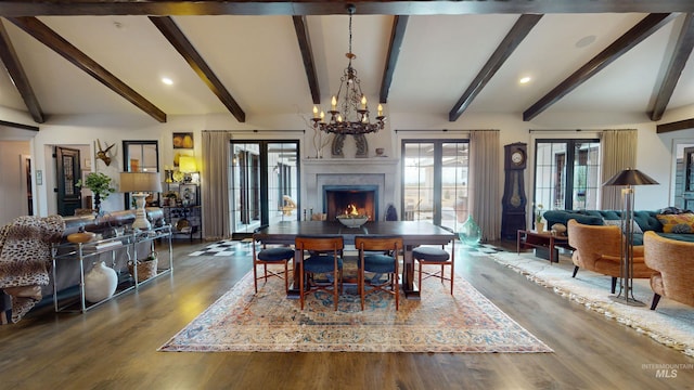 dining room with lofted ceiling with beams, a high end fireplace, wood finished floors, an inviting chandelier, and french doors