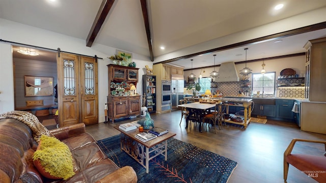 living room featuring lofted ceiling with beams, dark wood-type flooring, a barn door, and recessed lighting