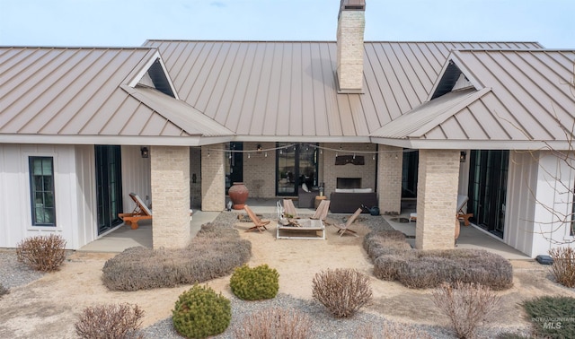 rear view of house with a patio, a standing seam roof, and metal roof