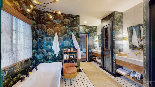 interior space featuring a sink, a freestanding tub, two vanities, and a chandelier