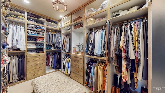 spacious closet with carpet floors and a chandelier