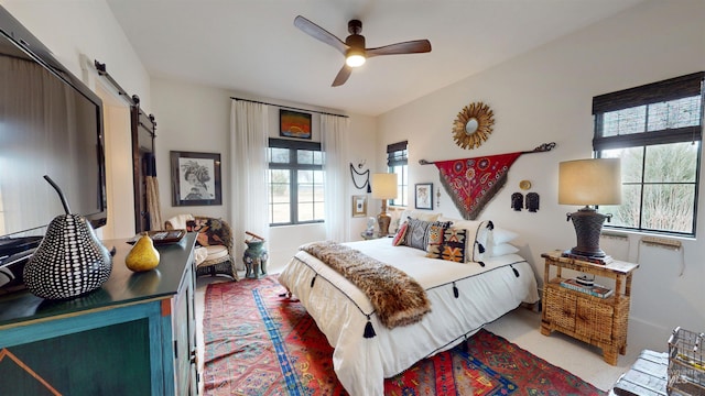 bedroom with a barn door, carpet flooring, and a ceiling fan