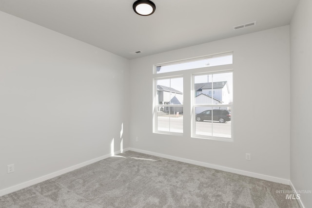 carpeted empty room featuring visible vents and baseboards