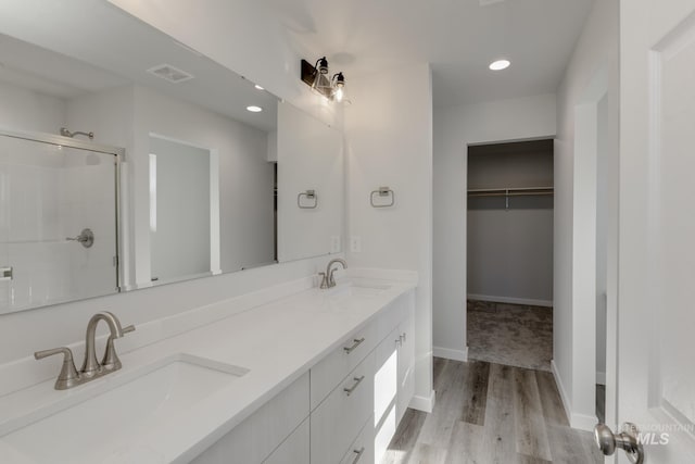 full bath with wood finished floors, a stall shower, a spacious closet, and a sink