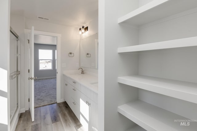 full bath featuring double vanity, visible vents, a sink, and wood finished floors
