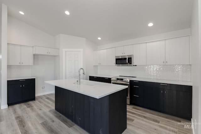 kitchen with dark cabinets, a sink, stainless steel appliances, white cabinetry, and lofted ceiling